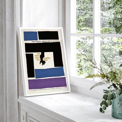 Movie poster for The Man with the Golden Arm by Saul Bass featuring bold abstract shapes and a stylized arm and hand in vibrant colors, framed and displayed in home decor