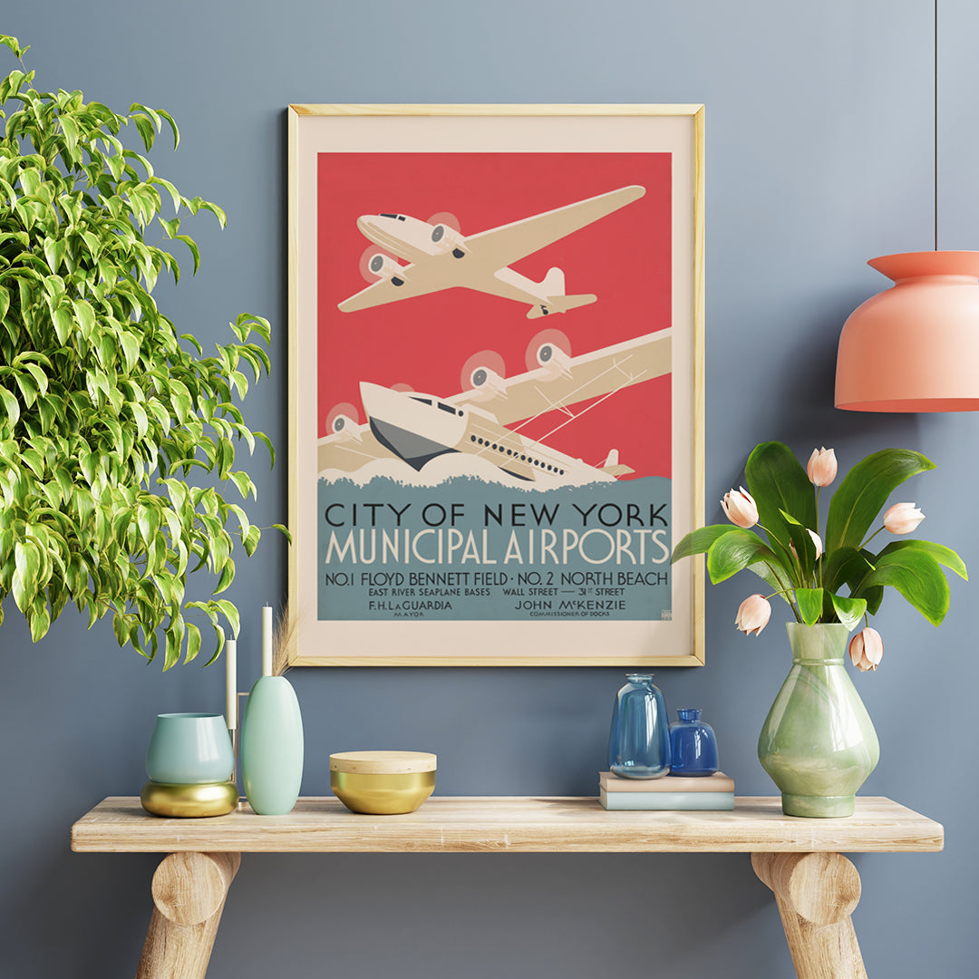 Vintage poster of stylized airplanes flying over water for City of New York municipal airports featuring bold artwork title and locations Floyd Bennett Field and North Beach, framed and displayed in home decor