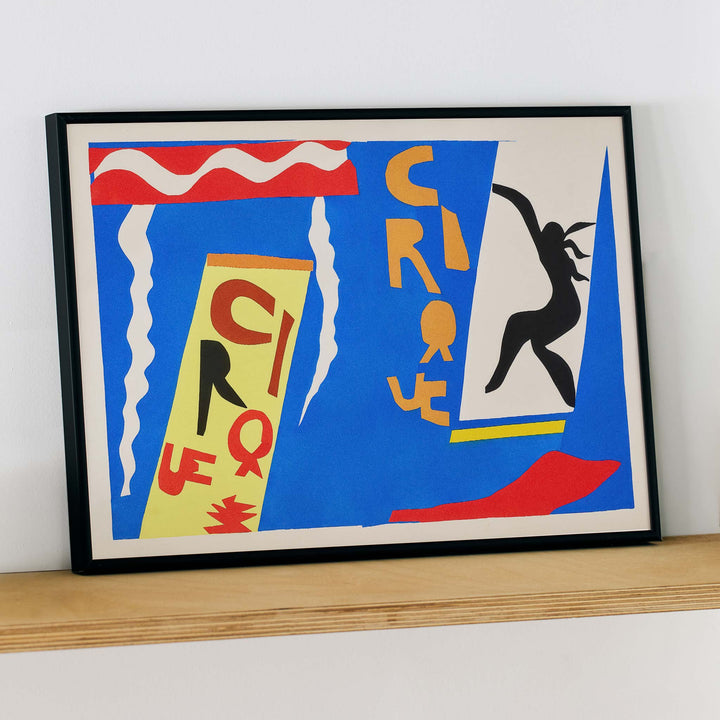 Henri Matisse Cirque poster with black acrobat silhouette, cut-paper circus lettering and white streamers on blue, with wooden magnetic frame on white background