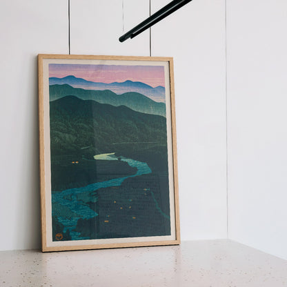 Ecchu Umidani Pass by Kawase Hasui landscape artwork showing mountains and a winding river at dawn and dusk, framed and displayed in modern living room decor