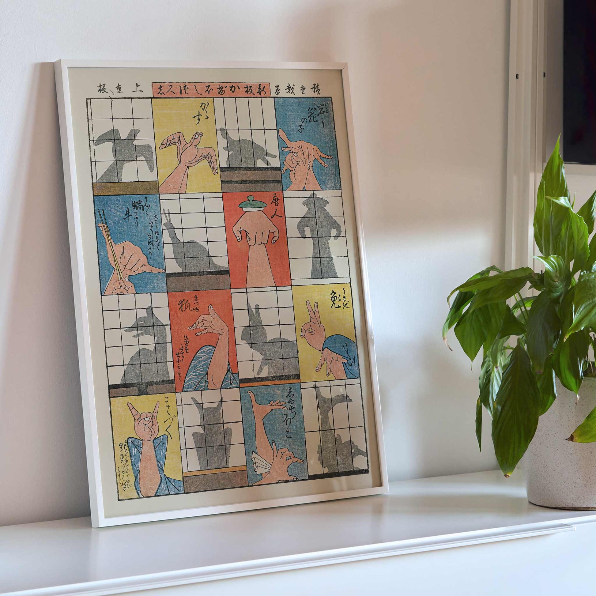 Utagawa Hiroshige Eight Shadow Figures poster with colorful hand gestures and ukiyo-e style panels, framed and displayed in modern living room decor