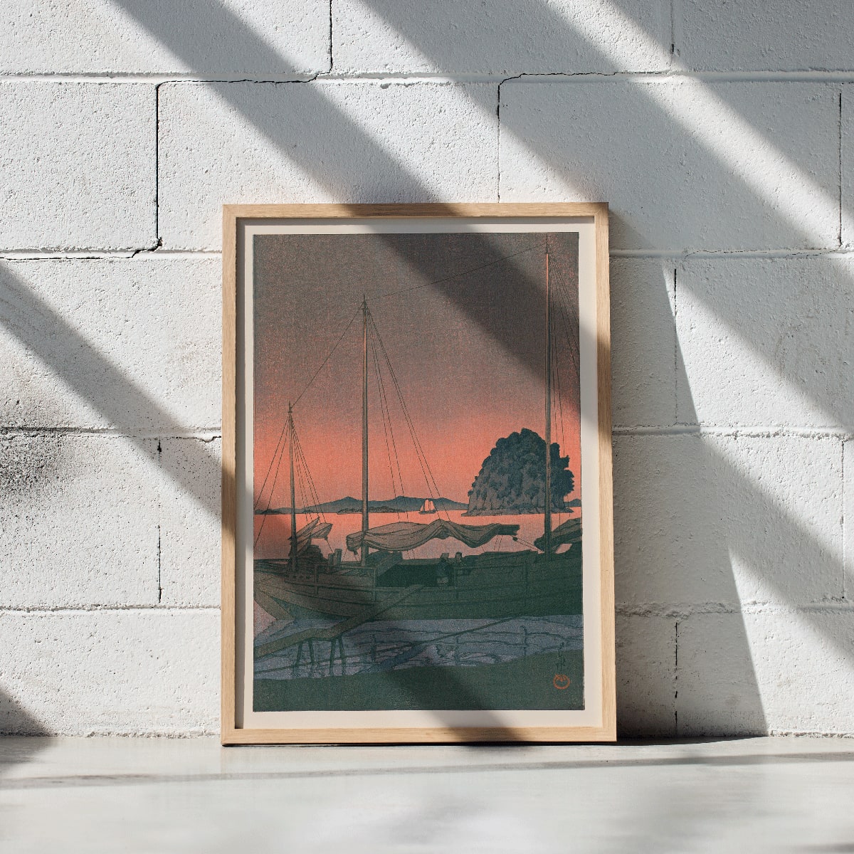 Ukiyo e Harbour Sunset by Kawase Hasui with boats docked at sunset tranquil evening sky island and mountains in background, framed and displayed in modern living room decor