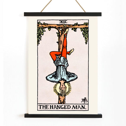 Hanged Man Tarot Card by Rider Waite, figure hanging upside down from wooden structure, mystical poster art, with wooden magnetic frame on white background